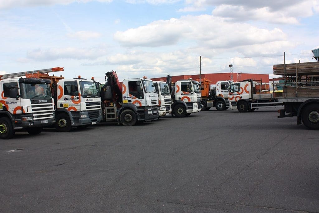 Row of Alltask trucks carrying scaffolding material.